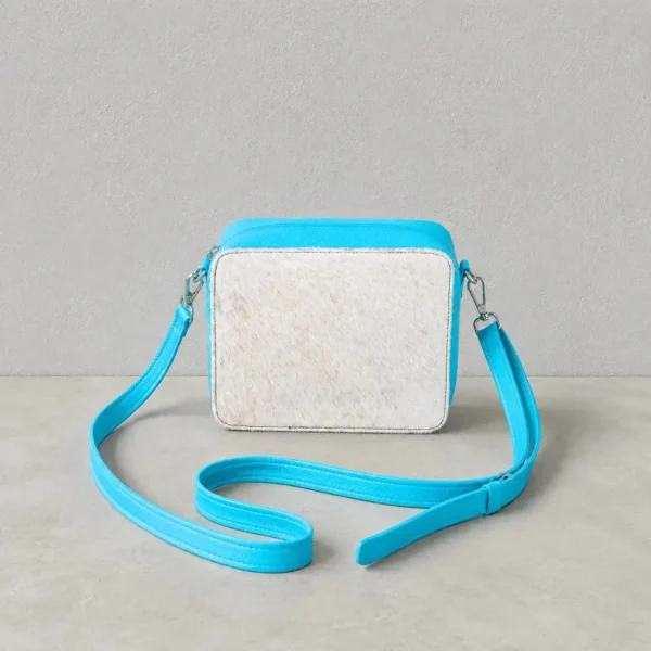 Leather cowhide box style crossbody bag with turquoise strap, brown and white cowhide texture, structured purse design and adjustable shoulder strap