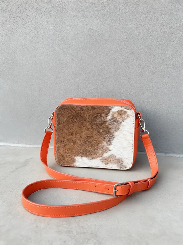 Orange cowhide crossbody bag with box style shape, cow finish leather, long strap, large compartment and inside pocket