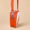 Orange cowhide crossbody bag with box style shape, cow finish leather, long strap, large compartment and inside pocket