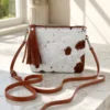 Cowhide mobile phone pouch square style with brown and white cowhide pattern, tan leather strap, zipper pocket and adjustable shoulder strap